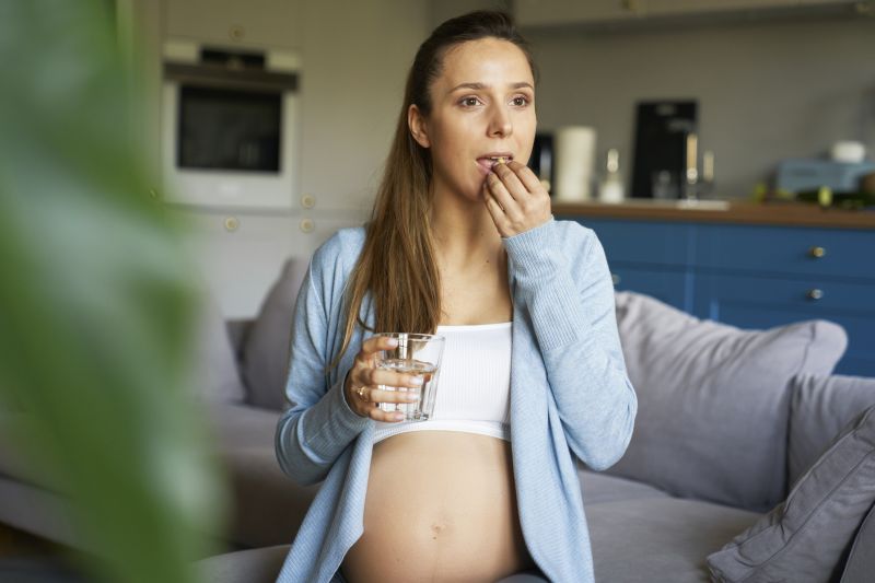 Pregnancy woman taking a pill of vitamins