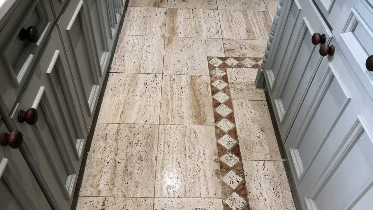 Worn travertine kitchen floor showing dull traffic areas and natural color variation